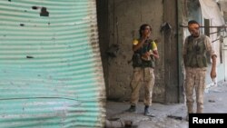 2016年8月7日，敘利亞民主力量戰鬥人員在阿勒頗曼比季的一個商店內​​查看一具屍體。他們說，那是伊斯蘭國戰鬥員的屍體。