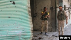 Syria Democratic Forces (SDF) fighters inspect a dead body of what they said was an Islamic State fighter inside a shop in Manbij, in Aleppo Governorate, Syria, August 7, 2016.