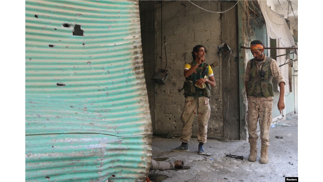 Syria Democratic Forces (SDF) fighters inspect a dead body of what they said was an Islamic State fighter inside a shop in Manbij, in Aleppo Governorate, Syria, August 7, 2016.