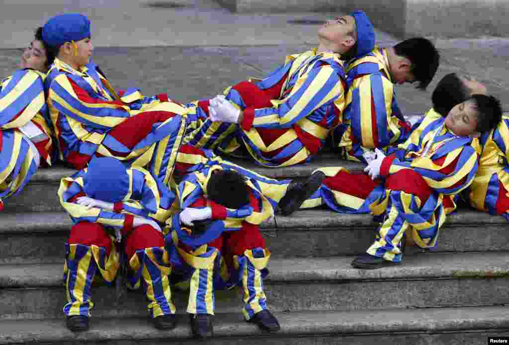 Schoolchildren dressed as Swiss Guards rest as they wait for the arrival of Pope Francis outside the Manila Cathedral in Manila, The Philippines.