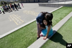 FILE - Sandra Collins, executive director and founder of enGender, hugs her child Scarlett at the Bay Area Rainbow Day Camp in El Cerrito, Calif., July 11, 2017.