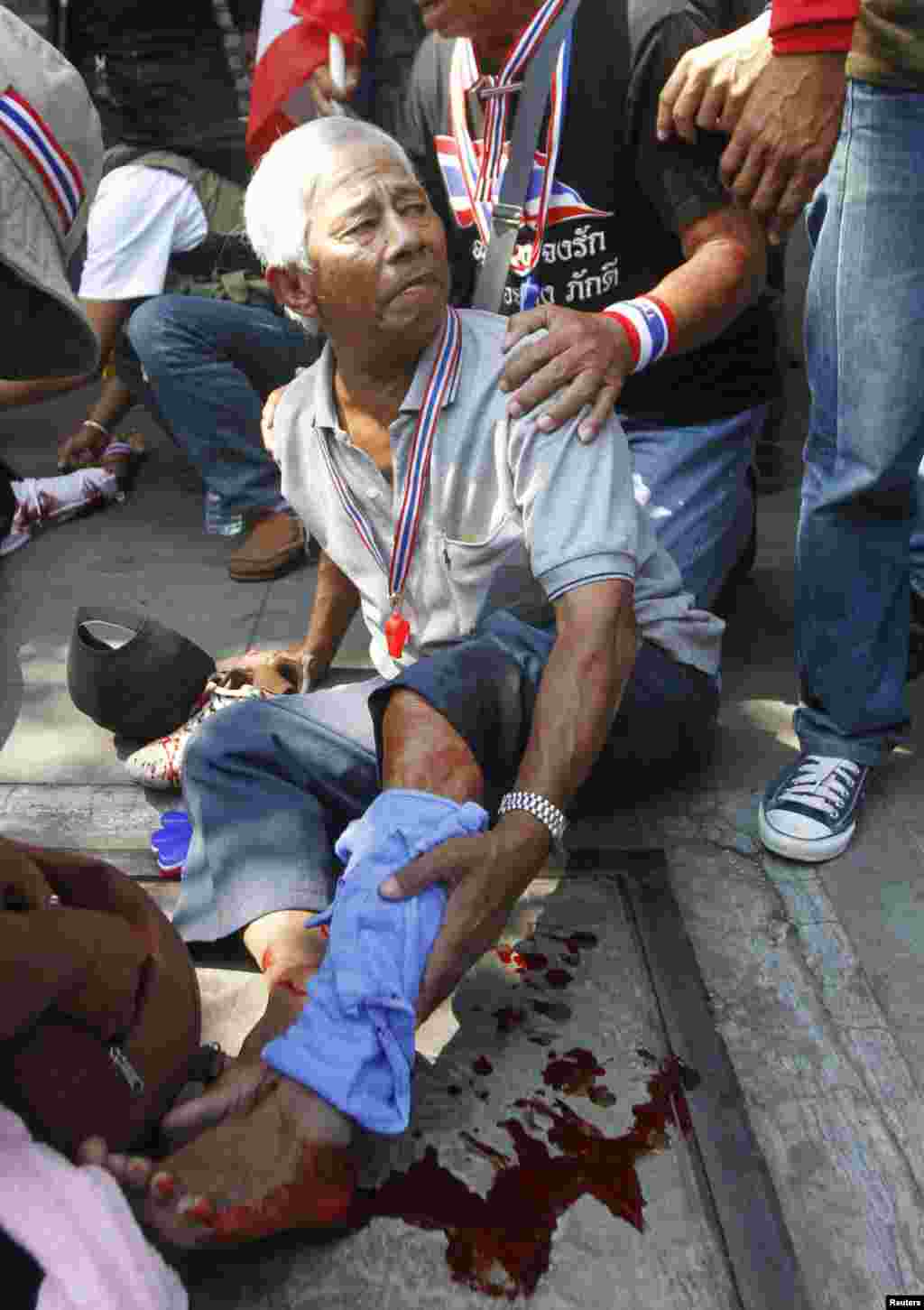 Anti-government protesters help a fellow protester injured in a grenade attack during a rally in Bangkok, Jan. 17, 2014.