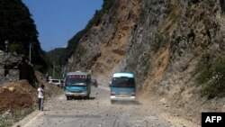  Two buses make their way across a road full of fallen rocks after a series of earthquakes, one of them measuring magnitude 5.7, hit the area near Zhaotong municipality at the border of southwest China's Yunnan and Guizhou province on September 7, 2012. 