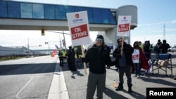 FILE Unifor worker Claude Robitaille holds a sign at GM's Oshawa assembly complex on Oct. 10, 2023. The Canadian union announced early Oct. 30, 2023, it would commence strikes at Stellanis facilities in the country.