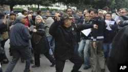 A police officer faces protesters during a demonstration against the Constitutional Democratic Rally - RCD, the party of deposed President Ben Ali, in the center of Tunis, 18 Jan 2011