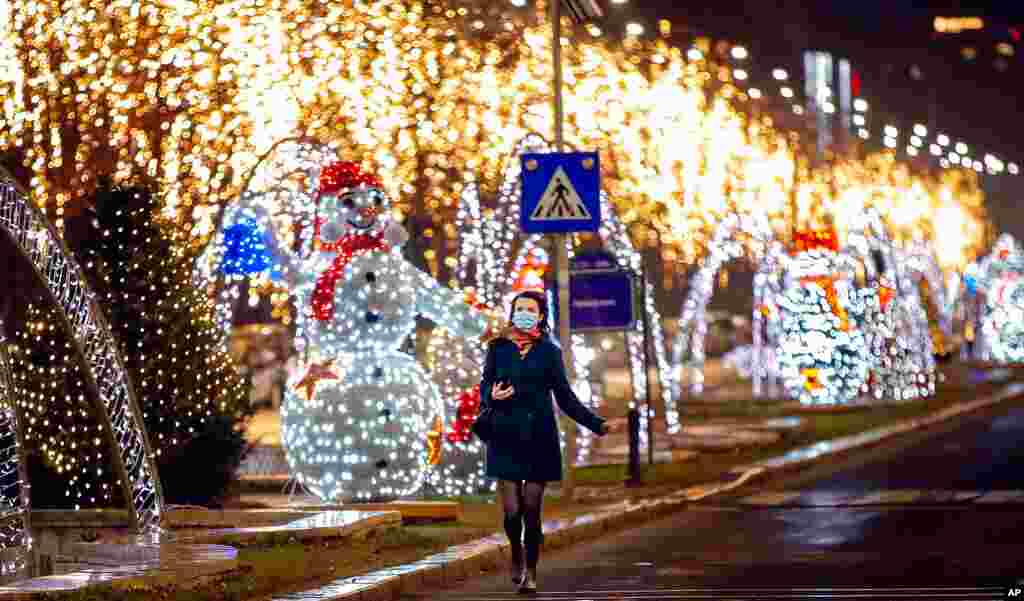 A woman runs by decorations near the parliament, a traditional place for street celebrations on New Year's Eve, in Bucharest, Romania, Dec. 31, 2020. Public celebrations and fireworks were canceled due to the coronavirus pandemic.