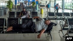 Seorang pria tertidur di terminal bus yang tidak biasanya sepi di Surabaya di tengah kekhawatiran penyebaran virus corona COVID-19, Selasa, 24 Maret 2020. (Foto: Juni Kriswanto/AFP)