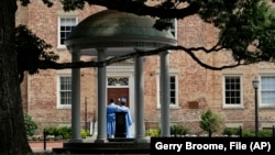 FILE - Graduates of the University of North Carolina take pictures at the Old Well on campus in Chapel Hill, N.C., June 30, 2020. (AP Photo/Gerry Broome, File)