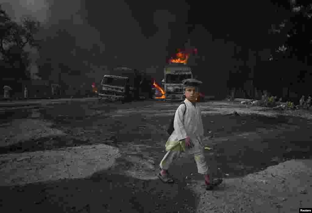 نوشہرہ میں ٹینکرز کو لگی آگ کے سامنے سے ایک بچہ گزر رہا ہے