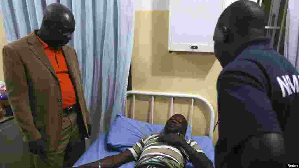 Air Commondore Charles Otegbade, Head of Search and Rescue of the Nigerian Emergency Management Agency (NEMA) visits a man shot in the chest, after fleeing the Central African Republic, at the Nigeria Air Force base clinic after his arrival at the airport.