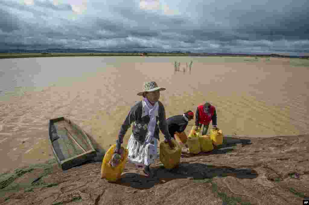 Residents cross a flooded area in Madagascar&#39;s capital, Antananarivo, to collect fresh water. Cyclone Enawo hit land Tuesday, claiming the lives of at least five people and forcing some 10,000 people abandon their homes.