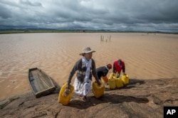 Residents cross flooded land and canal in Madagascar's capital Antananarivo, to collect fresh water, March 10, 2017.