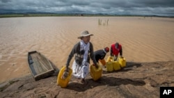 Residents cross flooded land and canal in Madagascar's capital Antananarivo, to collect fresh water, March 10, 2017. 