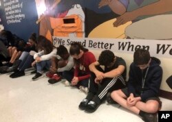 Estudiantes en Seminole Middle School en Plantation, Florida, participan en un momento de silencio el jueves, 14 de febrero de 2019, en recuerdo de los 14 estudiantes asesinados hace un año hoy en la escuela secundaria Marjory Stoneman Douglas.