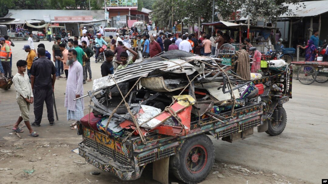 Warga berkumpul di dekat lokasi puing-puing bus yang jatuh ke selokan pinggir jalan di daerah Shibchar di distrik Madaripur, Bangladesh, Minggu, 19 Maret 2023.