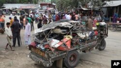 Warga berkumpul di dekat lokasi puing-puing bus yang jatuh ke selokan pinggir jalan di daerah Shibchar di distrik Madaripur, Bangladesh, Minggu, 19 Maret 2023.