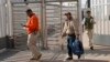 Carlos Catarldo Gomez, of Honduras, center, is escorted by Mexican officials after leaving the United States, the first person returned to Mexico to wait for his asylum hearing date, in Tijuana, Mexico, Jan. 29, 2019.