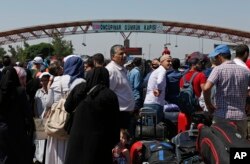 In this June 13, 2017 photo, Syrians living in Turkey wait to cross into Syria at the Oncupinar border crossing, near the town of Kilis, Turkey.