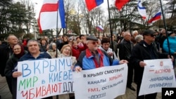 Pro-Russia demonstrators holding Russian and Crimean flags and posters rally in front of the local parliament building in Crimea's capital Simferopol, Ukraine, March 6, 2014.