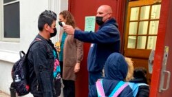 John Marro, the dean of students at the American Sign Language and English Lower School, in New York, takes students' temperatures as they arrive Jan. 3, 2022.