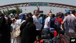 In this June 13, 2017 photo, Syrians living in Turkey wait to cross into Syria at the Oncupinar border crossing, near the town of Kilis, Turkey.