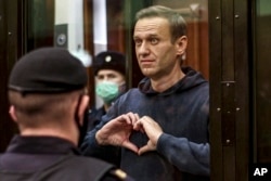 FILE - Alexei Navalny makes a heart shape with his hands during a trial in Moscow in 2021. (Moscow City Court via AP)