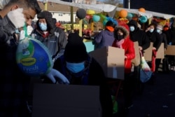 Residents receive free groceries, including a turkey, distributed by La Colaborativa, who gave out food for 3500 people over the course of the day, ahead of the Thanksgiving holiday in Chelsea, Massachusetts, Nov. 23, 2021.
