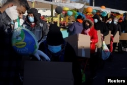 Residents receive free groceries, including a turkey, distributed by La Colaborativa, who gave out food for 3500 people over the course of the day, ahead of the Thanksgiving holiday in Chelsea, Massachusetts, Nov. 23, 2021.