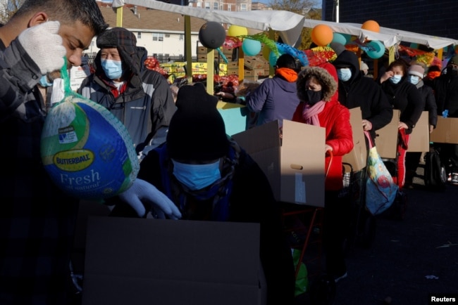 Residents receive free groceries, including a turkey, distributed by La Colaborativa, who gave out food for 3500 people over the course of the day, ahead of the Thanksgiving holiday in Chelsea, Massachusetts, Nov. 23, 2021.