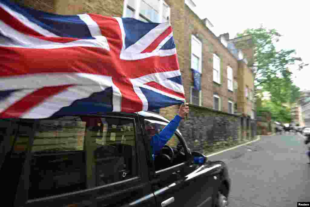 A taxi driver holds a Union flag, as he celebrates following the result of the EU referendum, in central London, Britain.