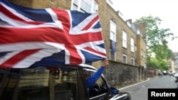 A taxi driver holds a Union flag, as he celebrates following the result of the EU referendum, in central London, Britain June 24, 2016. 