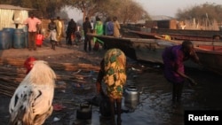 A women displaced by fighting in Bor county washes herself as another washes kettles in the village of Mingkamen on Jan. 14, 2014.