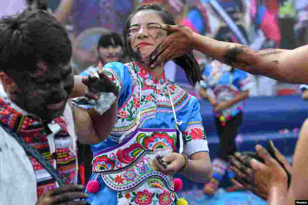 People smear black ash with hands onto each other to wish for good luck and fortune during a traditional festival of the Yi ethnic minority in Qiubei County, Yunnan province, China.