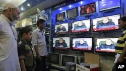 People watch Prime Minister of Pakistan Nawaz Sharif addressing the nation, at an electronic shop in Karachi, Aug. 19, 2013. 