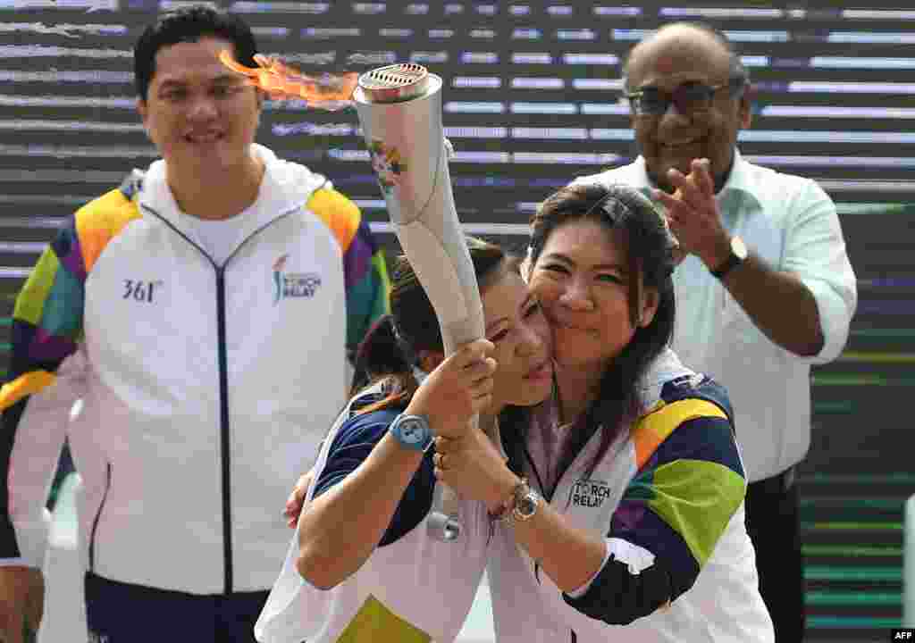 Petinju India, Mary Kom (depan kiri) dan mantan pebulu tangkis Indonesia Susi Susanti (depan kanan) yang menjadi duta obor Asian Games, berpelukan saat mereka memulai kirab obor Asian Games di New Delhi, 15 Juli 2018. (Foto:AFP)
