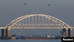 Russian jet fighters fly over a bridge connecting the Russian mainland with the Crimean Peninsula with a cargo ship beneath it after three Ukrainian navy vessels were stopped by Russia from entering the Sea of Azov via the Kerch Strait in the Black Sea, Crimea. (File)