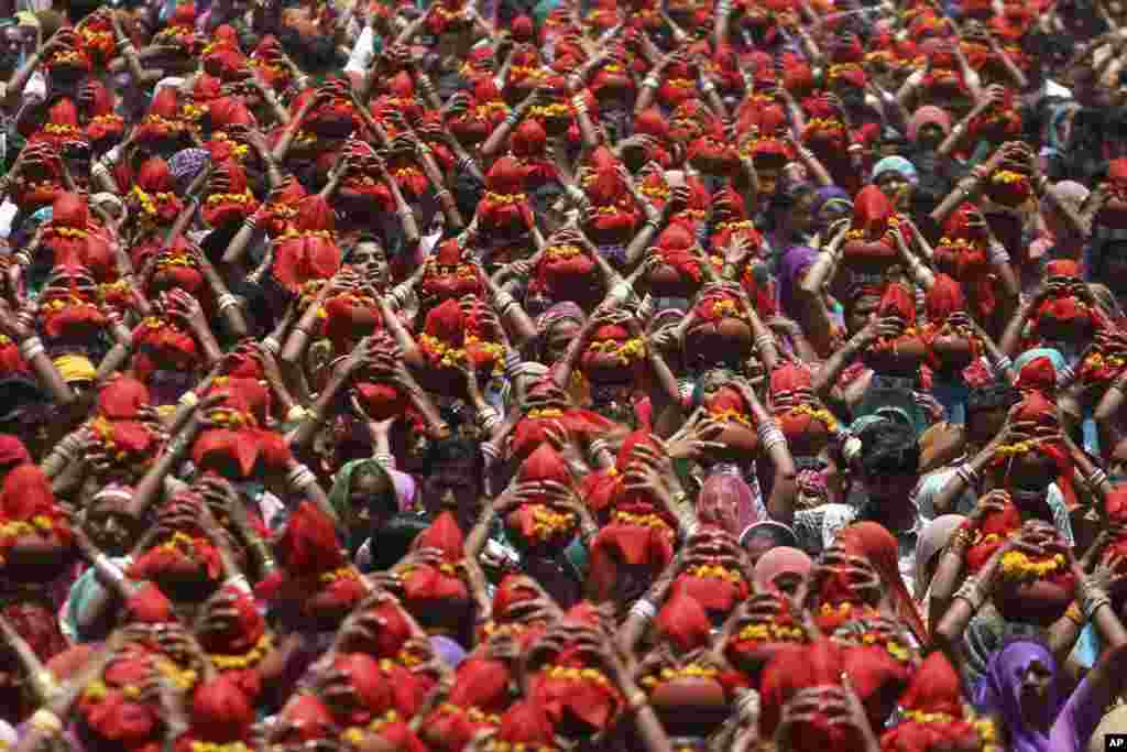 Indian women carry earthen pots covered with red cloth during a religious procession locally called Gangaji in Ahmadabad. Members of Sargara community organize a pilgrimage to the River Ganges, considered holy by the Hindus, in Haridwar after this ritualistic procession.