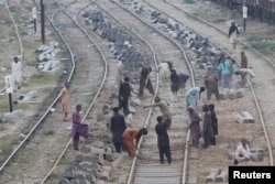 FILE - Laborers dig the ground before replacing concrete sleepers along railway tracks in Karachi, Pakistan, Jan. 11, 2018.