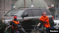 在雾霾中的北京，某停车场员工戴着面罩等待顾客。（2014年2月26日）