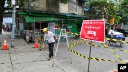 ကိုရိုနာဗိုင်းရပ်စ် ကူးစက်ပျံ့နှံ့မှု တိုးနေတဲ့ ရန်ကုန်မြို့မှာ အဝင်အထွက် ကန့်သတ်ပိတ်ဆို့ထားတဲ့ လမ်းတခုအနီး ဖြတ်သွားတဲ့ ဒေသခံတဦး။ (စက်တင်ဘာ ၁၁၊ ၂၀၂၀)