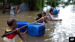 Residents wade through flood water by holding a float-attached pole as they evacuate their homes in Nakhon Ratchasima province, northeastern Thailand, 17 Oct 2010