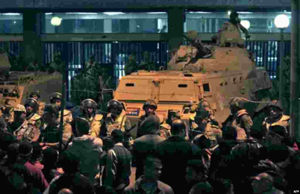 Army soldiers stand guard as anti-government protesters surround the state television building following Egyptian President Hosni Mubarak's televised speech, on the Corniche in downtown Cairo, Egypt Thursday, Feb. 10, 2011. Mubarak refused to step down or