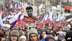 Para demonstran membawa bendera Rusia dan potret Boris Nemtsov bertuliskan "Jangan berbohong, jangan mencuri," berpawai untuk memperingati pembunuhan pemimpin oposisi, Boris Nemtsov, di Moscow, Rusia, Minggu, 24 Februari 2019.