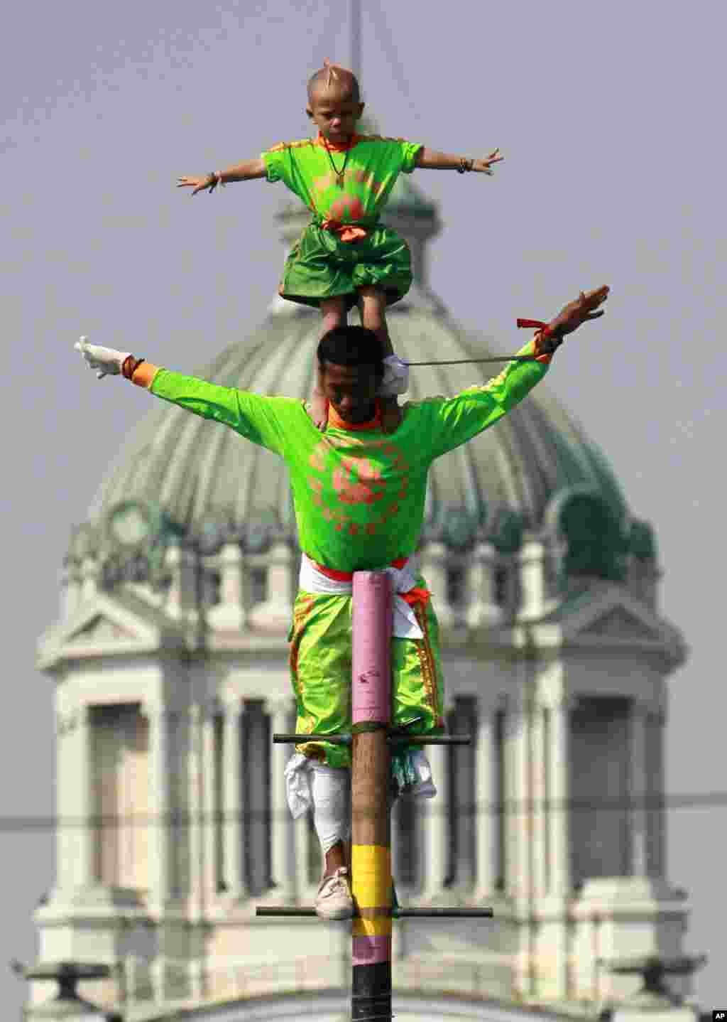 Two Thai boys perform acrobatics to entertain anti-government protesters during a rally at the Royal Plaza in Bangkok, Thailand. Tens of thousands of anti-government protesters marched through the streets of the Thai capital, reviving their campaign to force the resignation of Prime Minister Yingluck Shinawatra and seeking the country to reform before the election.