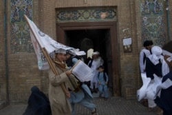 Seorang pendukung Taliban membawa bendera Taliban di sebuah masjid di Herat, Afghanistan, 10 September 2021. (Foto: WANA/West Asia News Agency via REUTERS)