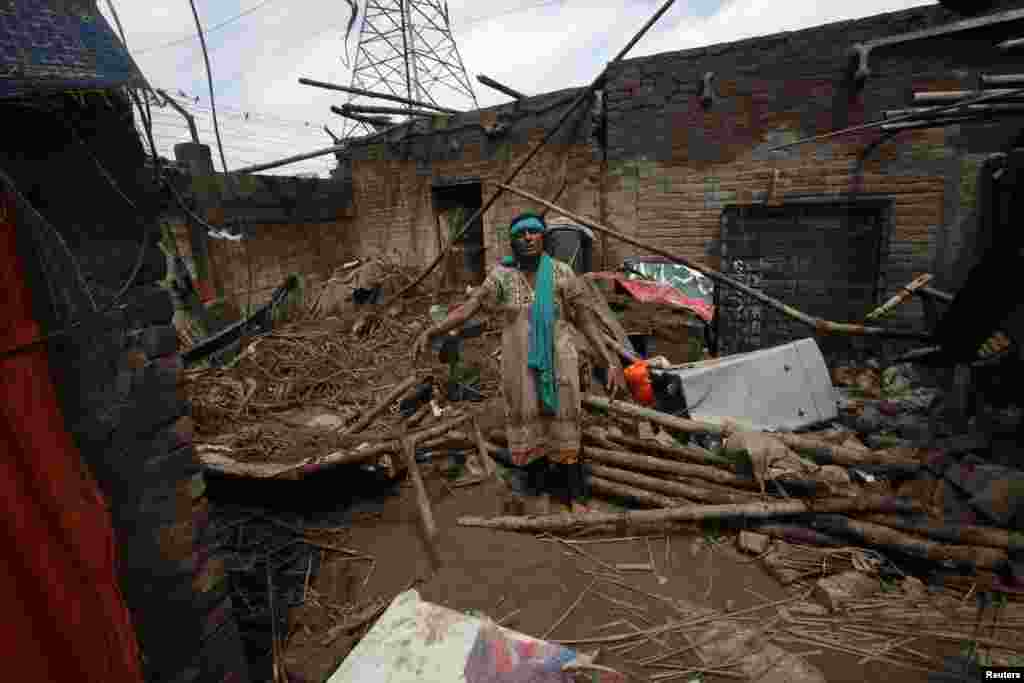 لاہور کی ایک رہائشی خاتون شدید بارش کے بعد اپنے گھر کے صحن میں تباہ ہونے والی چیزوں کو اکٹھا کر رہی ہے۔