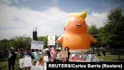在華盛頓舉行獨立日慶祝活動期間，反特朗普的示威者站在“特朗普寶寶”氣球前。(2019年7月4日)