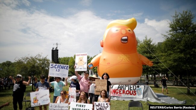在華盛頓舉行獨立日慶祝活動期間，反特朗普的示威者站在「特朗普寶寶」氣球前。(2019年7月4日)