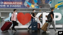FILE - Travelers pull their luggage through Boryspil International Airport, outside Ukraine's capital Kyiv, June 15, 2020.