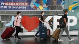 FILE - Travelers pull their luggage through Boryspil International Airport, outside Ukraine's capital Kyiv, June 15, 2020.